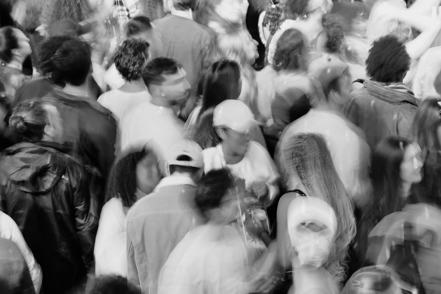 Black and white photo of a crowd of people, the people are in motion and therefore somewhat blurred