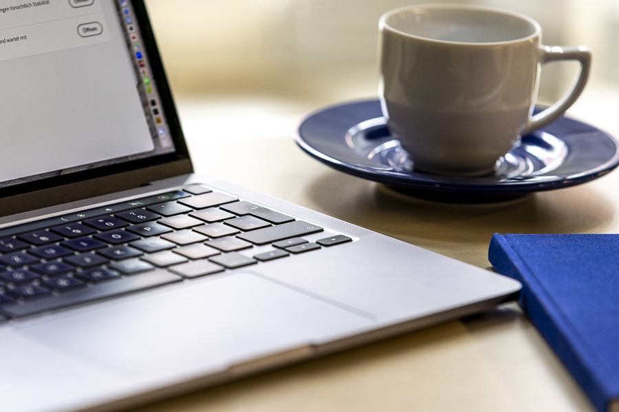 Bild des Laptops auf dem Tisch, Tasse und Notizbuch, Nahaufnahme